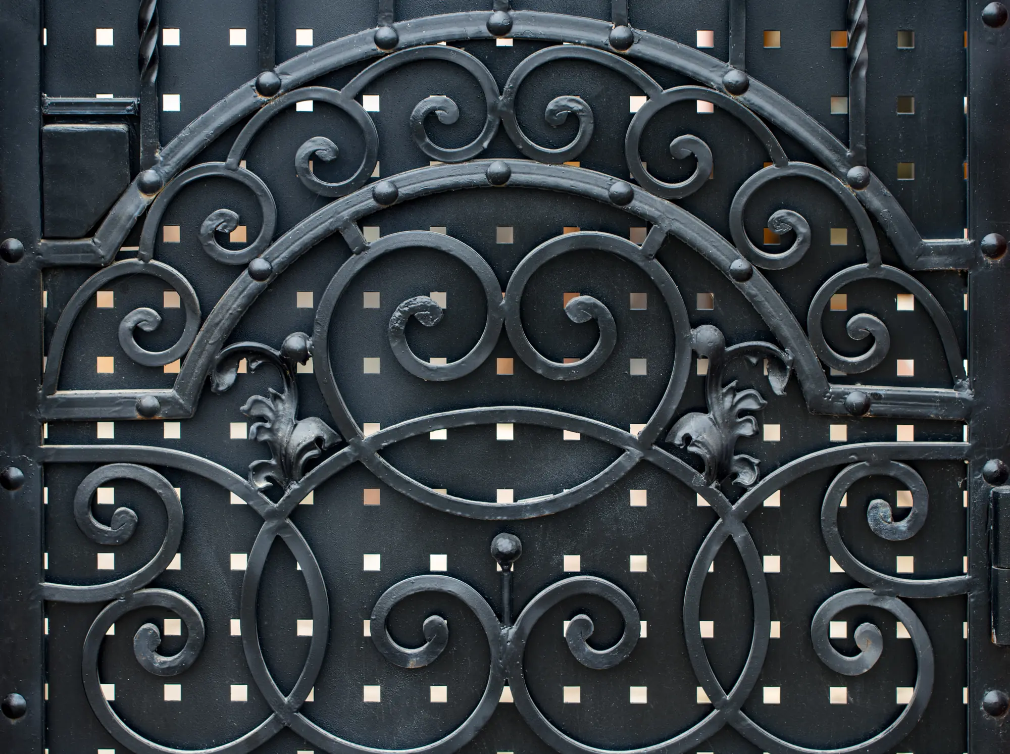 Détail d’un ouvrage en fer forgé : volutes et barreaux assemblés à la forge